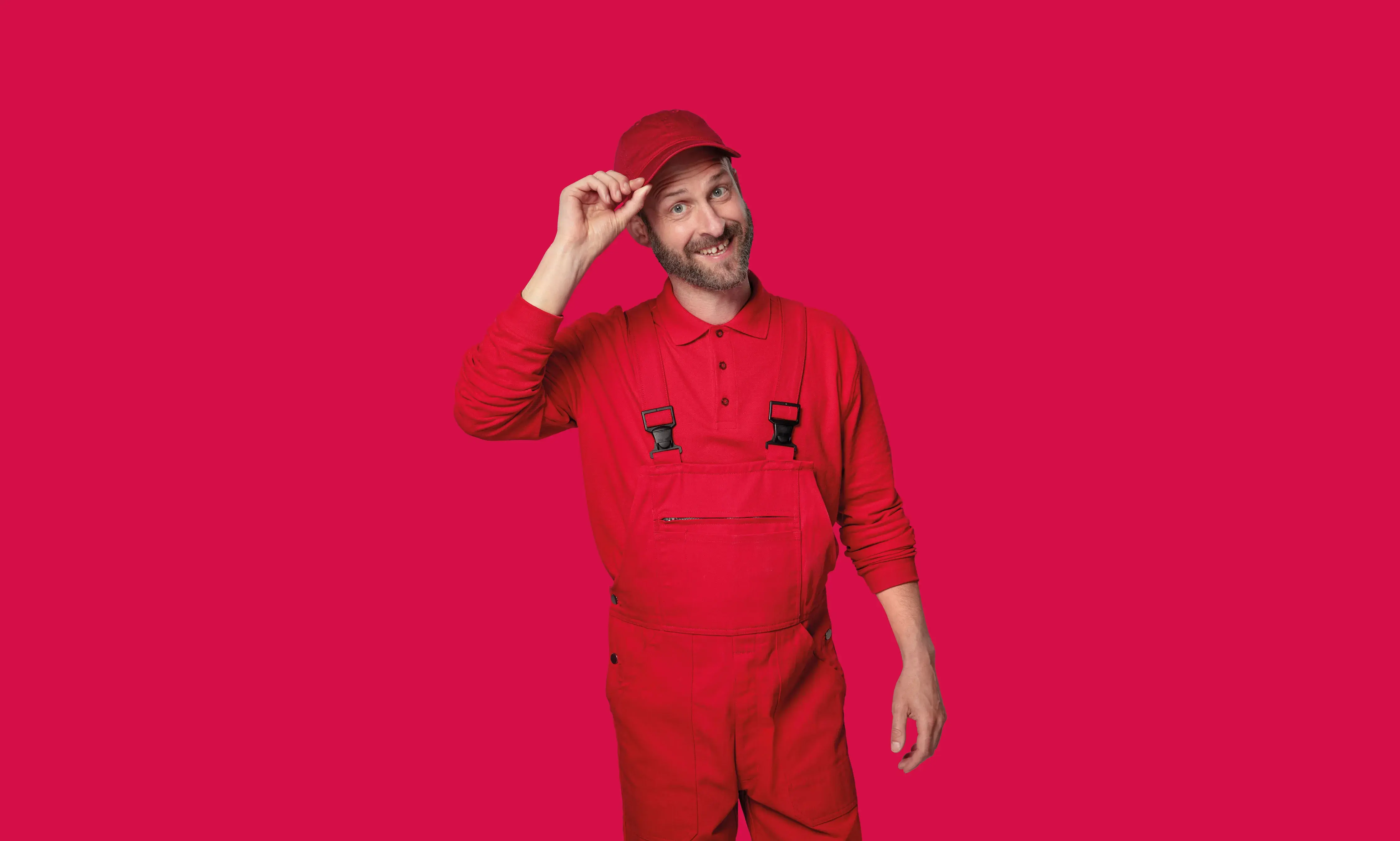 Mann in roter Arbeitskleidung lächelt vor knallrotem Hintergrund.